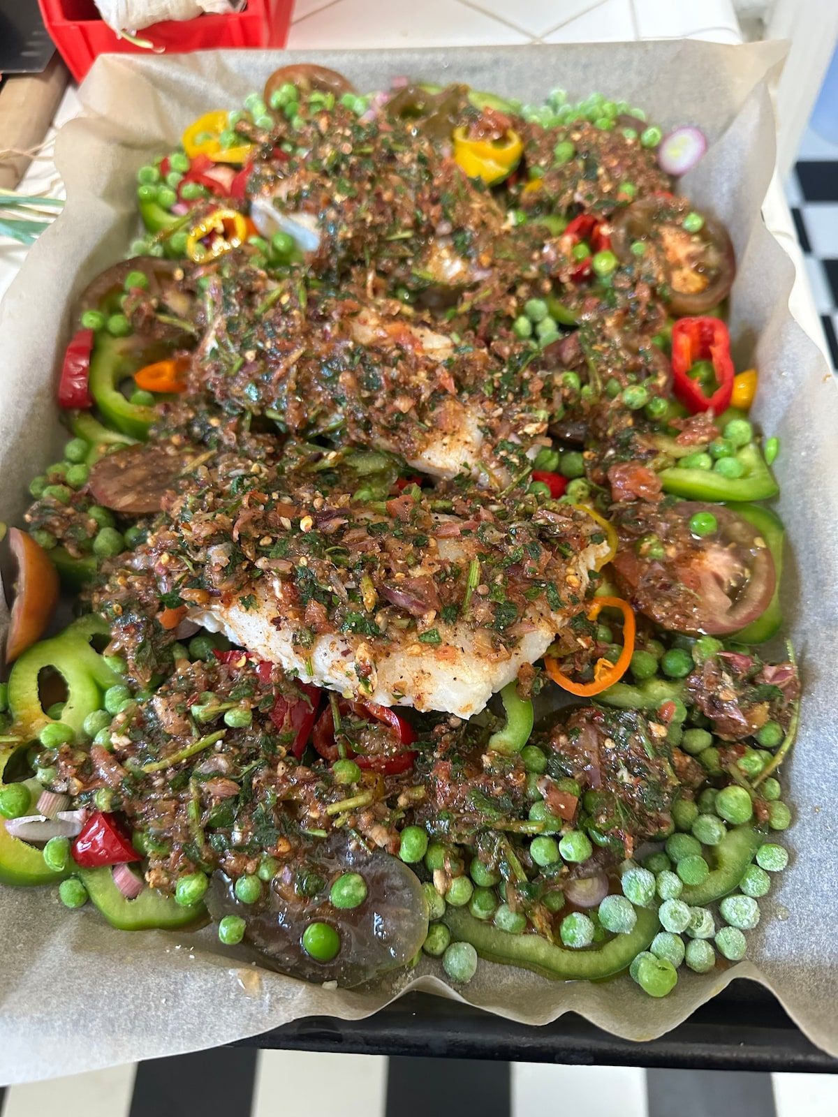 Fish fillets baked with chermoula, bell peppers, tomatoes and green peas.
