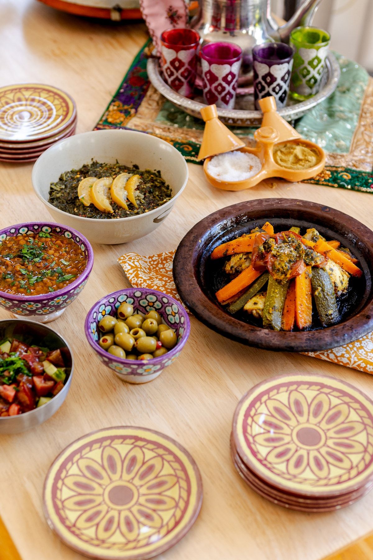 A spread of Moroccan salads and a vegetable tagine on hand-painted plates, with a tea set.