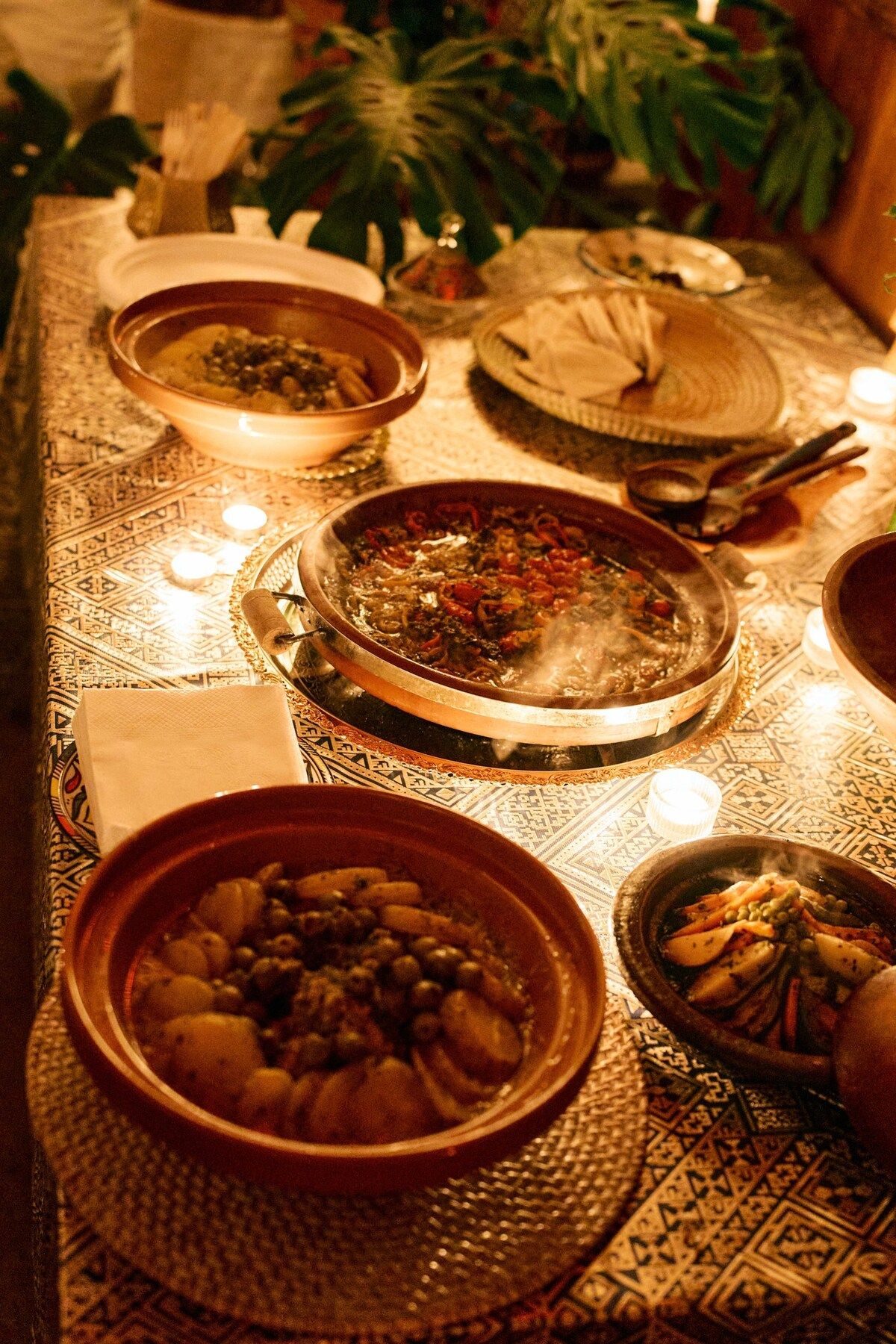 A candlelit Moroccan dinner spread with tagines and small dishes.