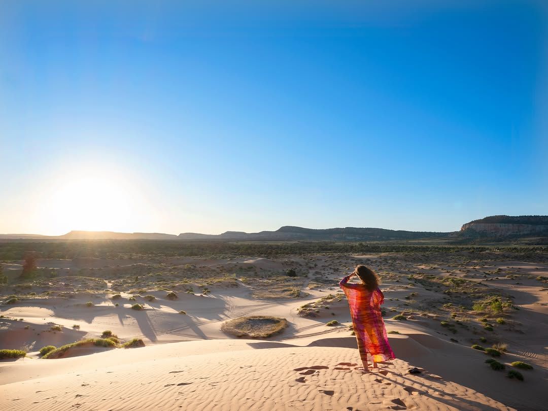 Chef Basmah in a red dress on sand dunes in golden light.