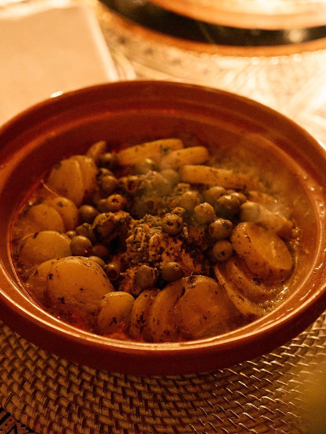 Close-up of a tagine with potatoes, green olives and herbs.
