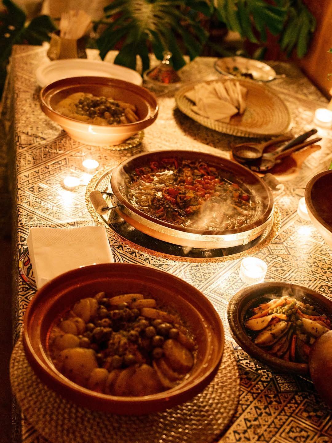 A candlelit table of Moroccan dishes: tagines, olives and salads.