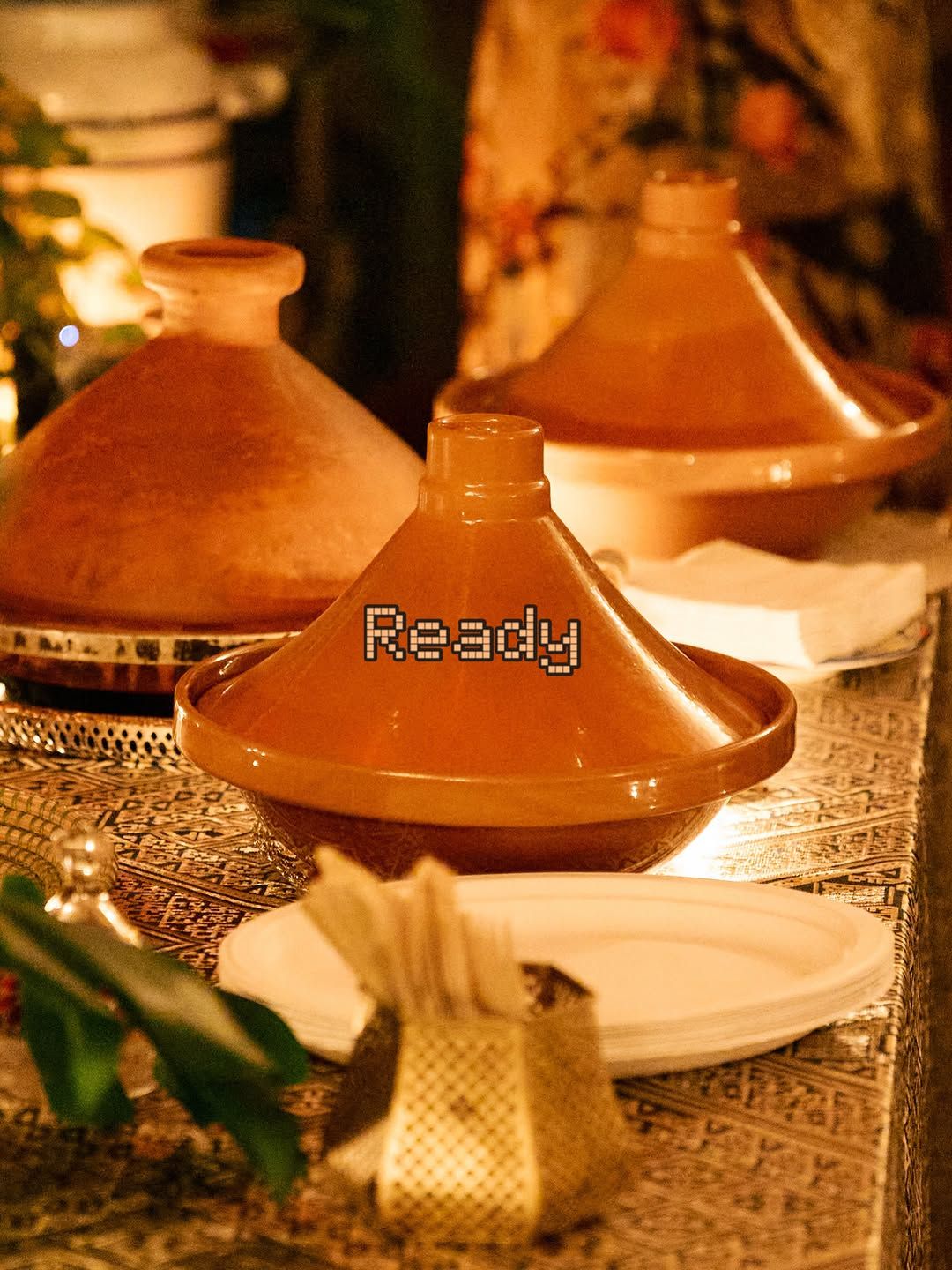 Clay tagines ready to serve on a candlelit table.