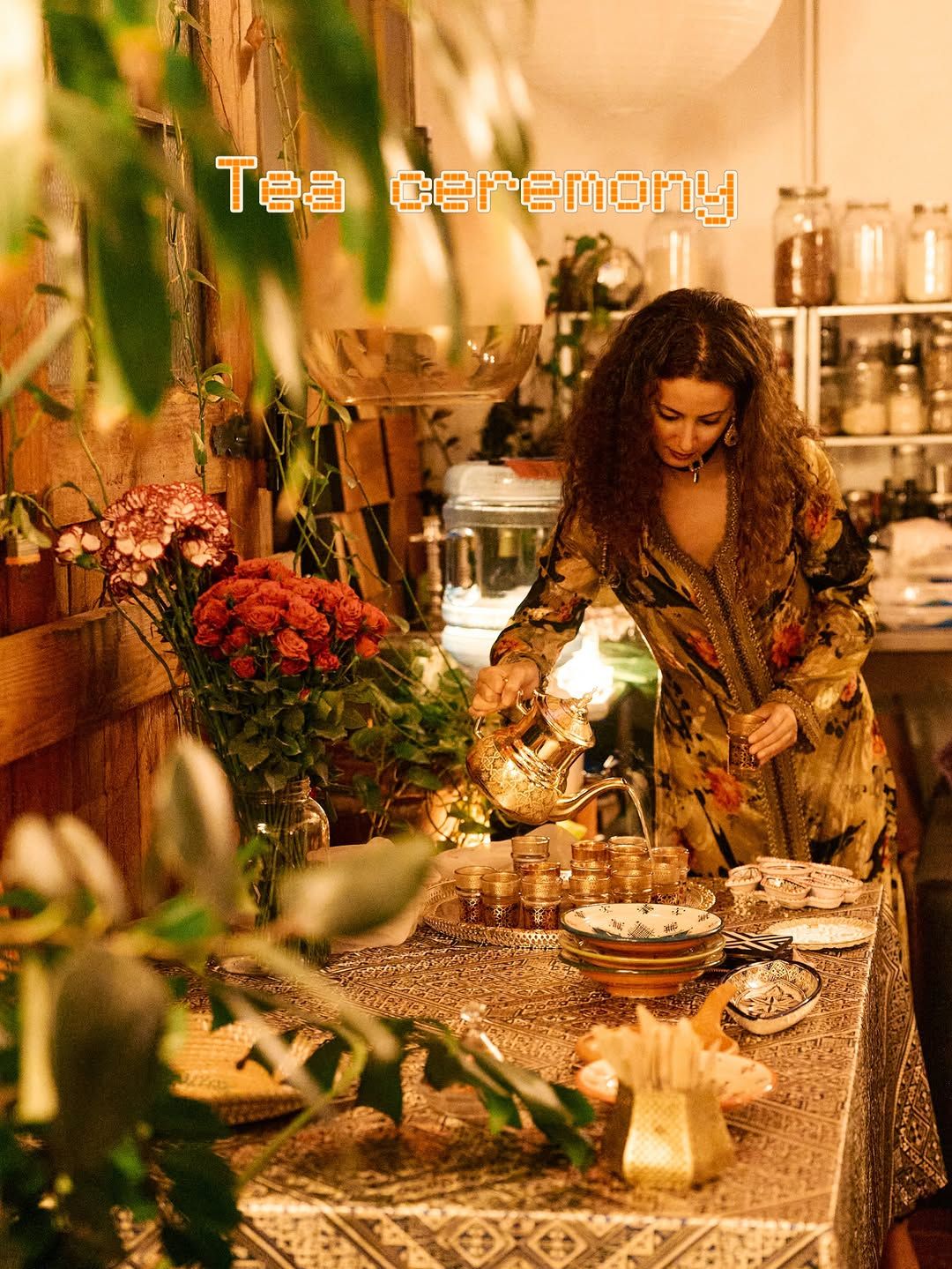 Chef Basmah pouring mint tea from a silver teapot at a candlelit table.